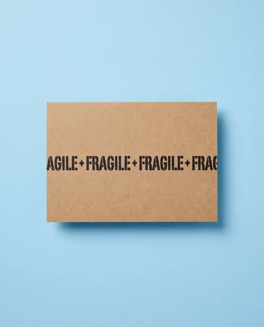 Kraft proof card on light blue: FRAGILE repeating on a single 14 mm line, printed with a Rolly M
